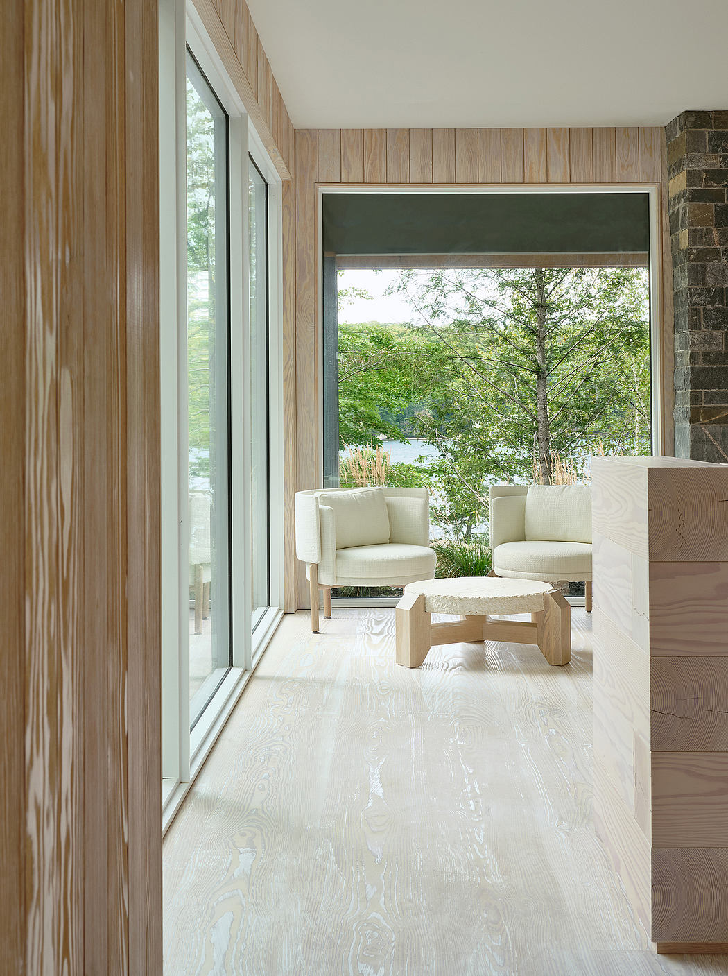 A cozy and contemporary living space with wooden walls, large windows, and minimal furnishings.