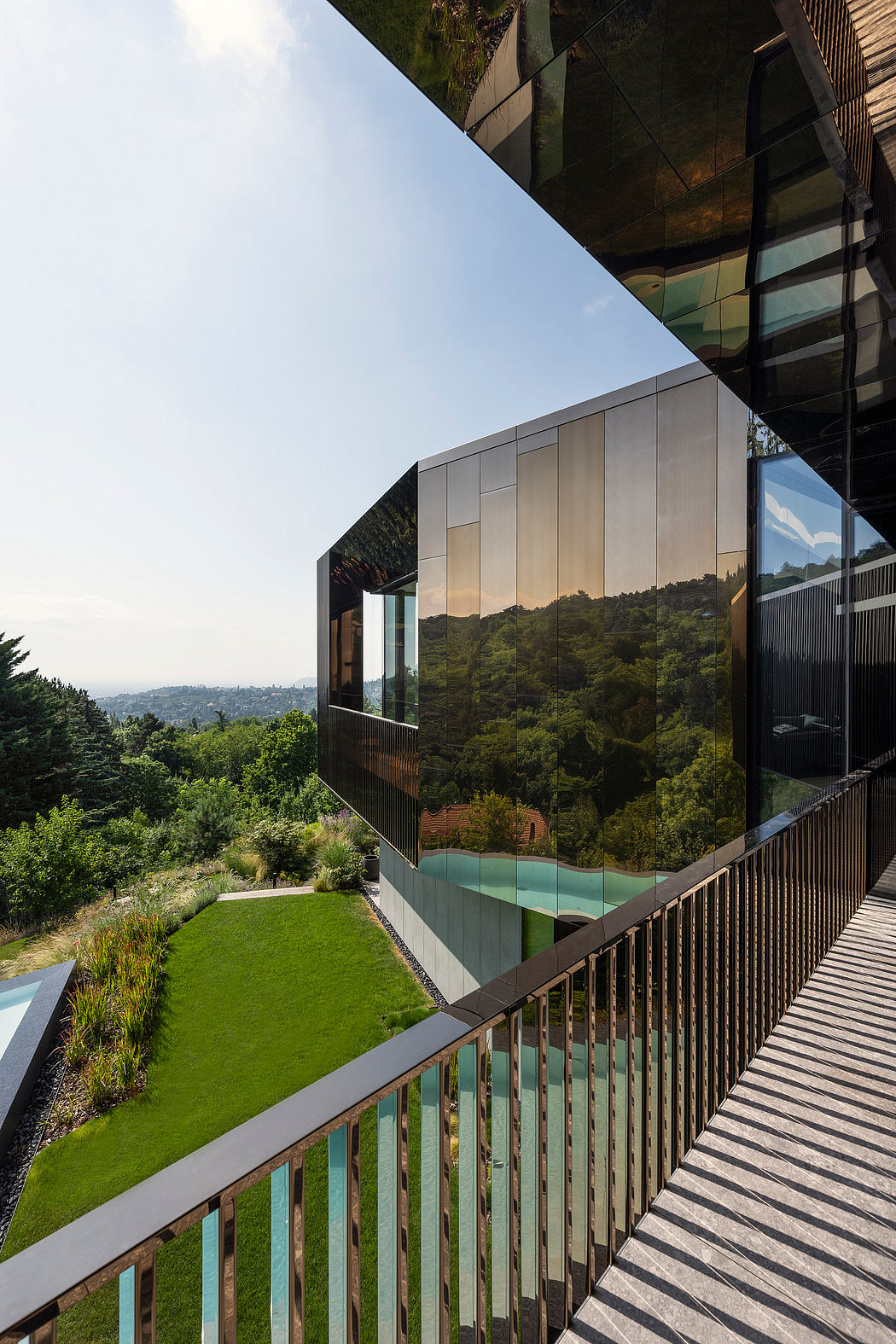 Striking architectural design with expansive glass windows, balconies, and lush greenery.