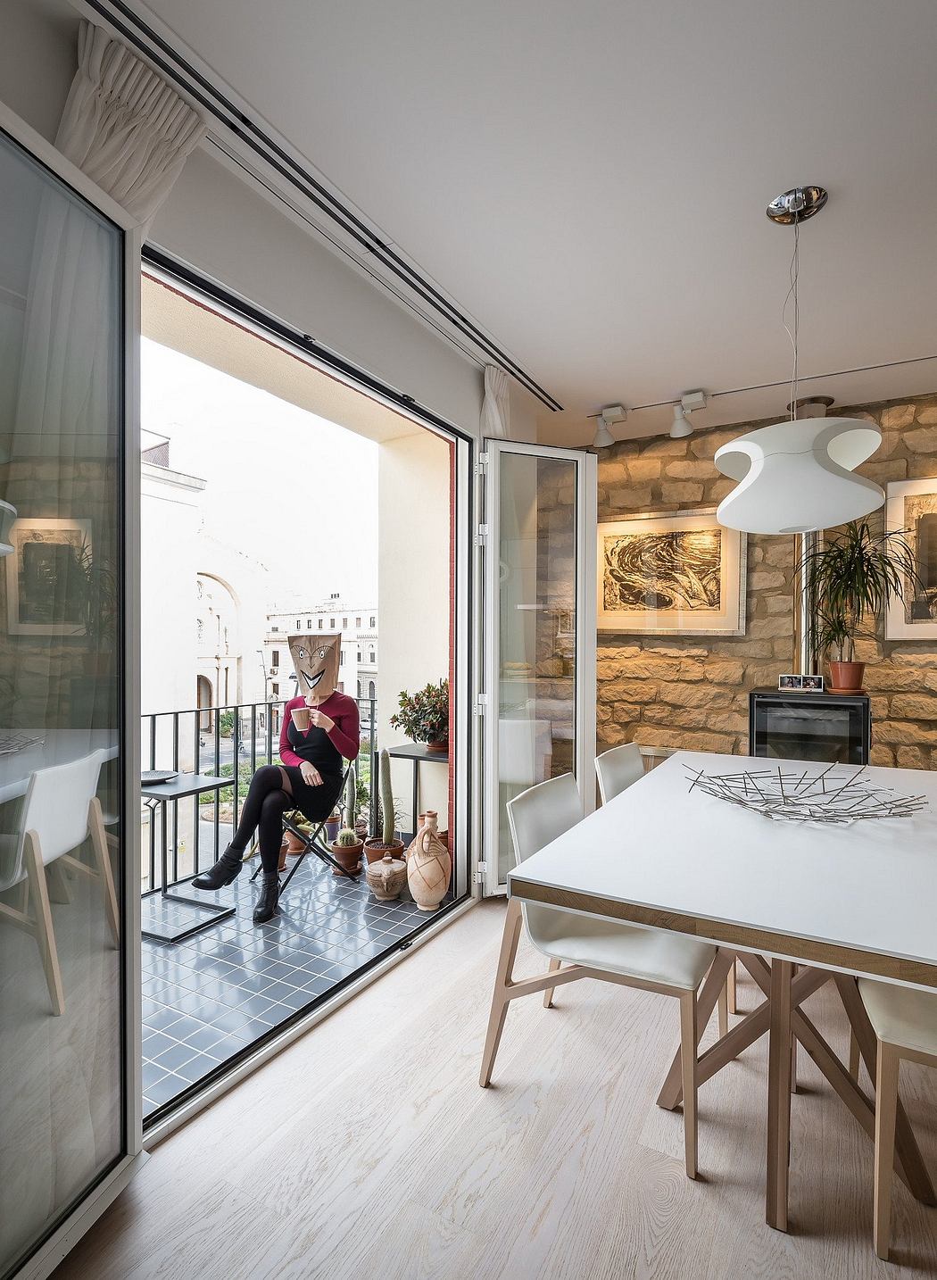 Elegant open-concept living space with large windows, rustic stone accent wall, and modern furnishings.