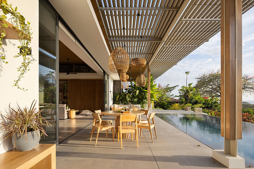 Expansive outdoor dining area with wooden trellis, pendant lights, and water feature.