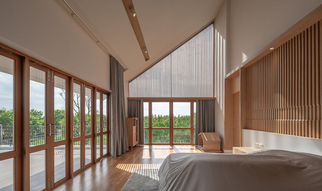 Spacious bedroom with floor-to-ceiling windows, wood paneling, and a serene outdoor view.