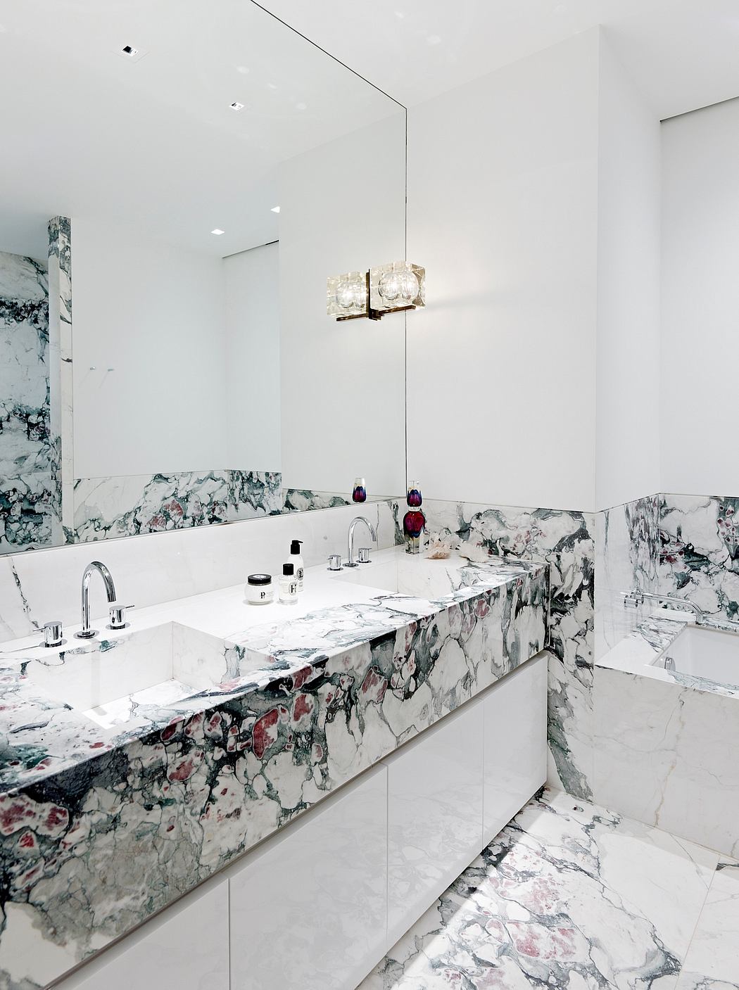 Luxurious bathroom with intricate marble surfaces, statement lighting fixture, and modern fixtures.