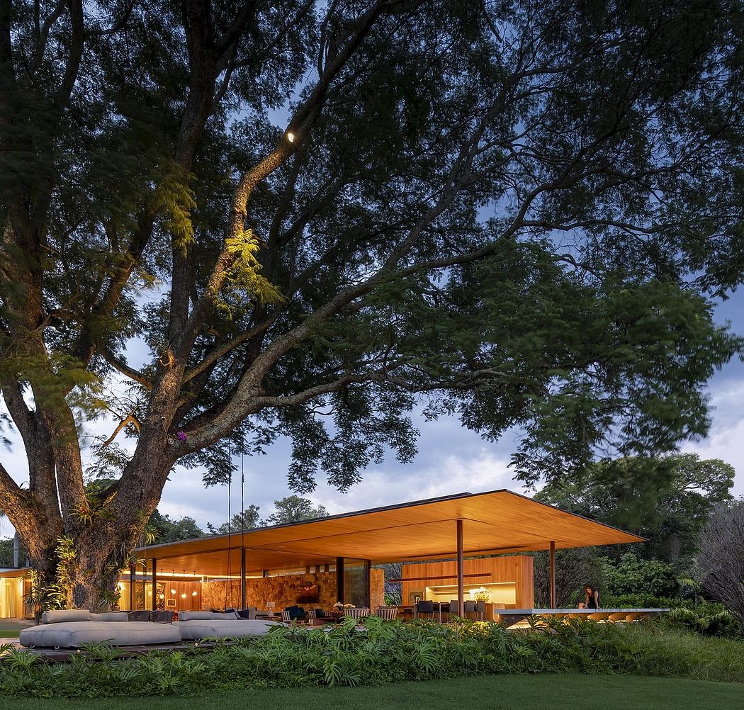 A modern, open-concept structure with a large overhanging roof amid lush greenery.