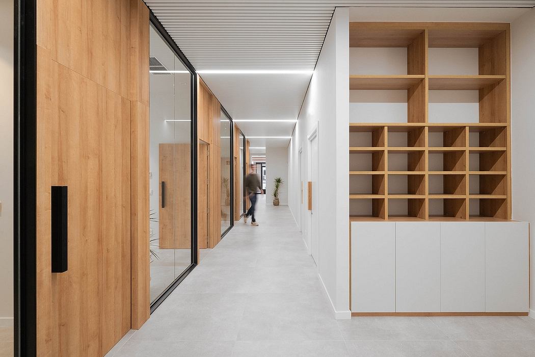 Modern office corridor with wood paneling, glass walls, and built-in storage shelves.