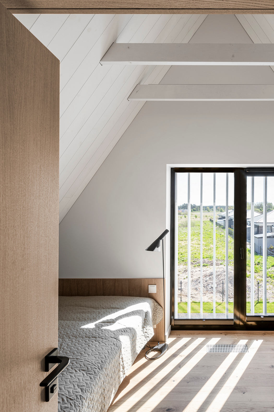 A cozy bedroom with wood-paneled walls, grid-patterned windows, and a quilted bed.