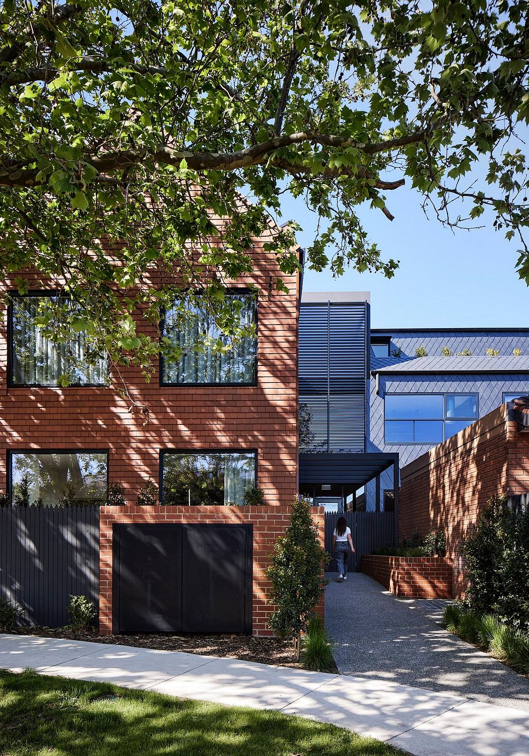 Striking modern brick home with large windows, geometric facades, and landscaping.