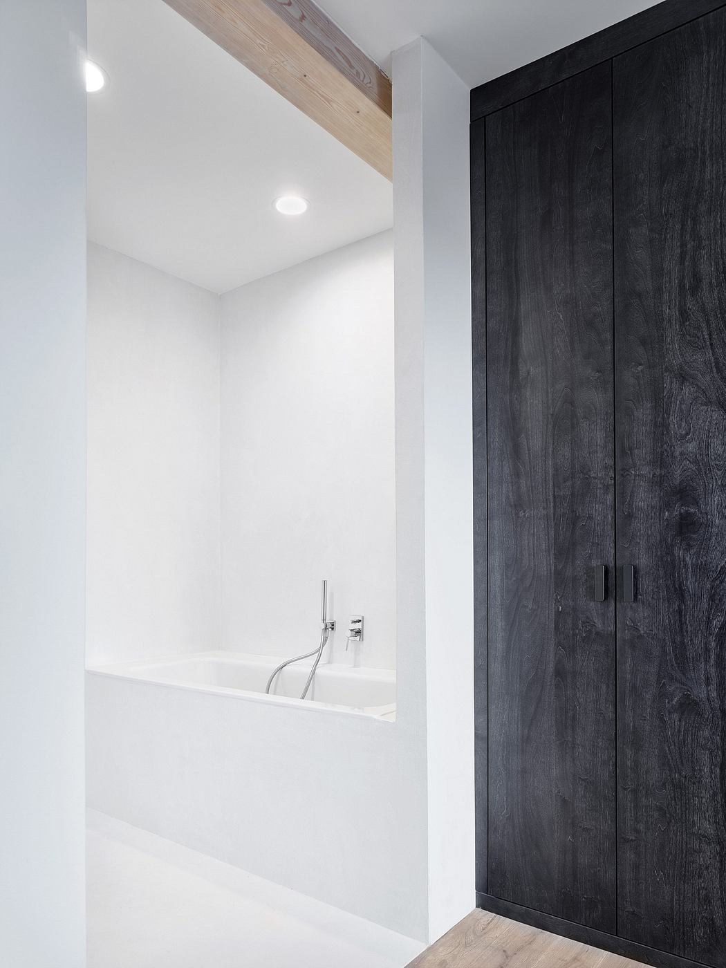 Modern minimalist bathroom with dark wood cabinets, white walls, and a freestanding bathtub.