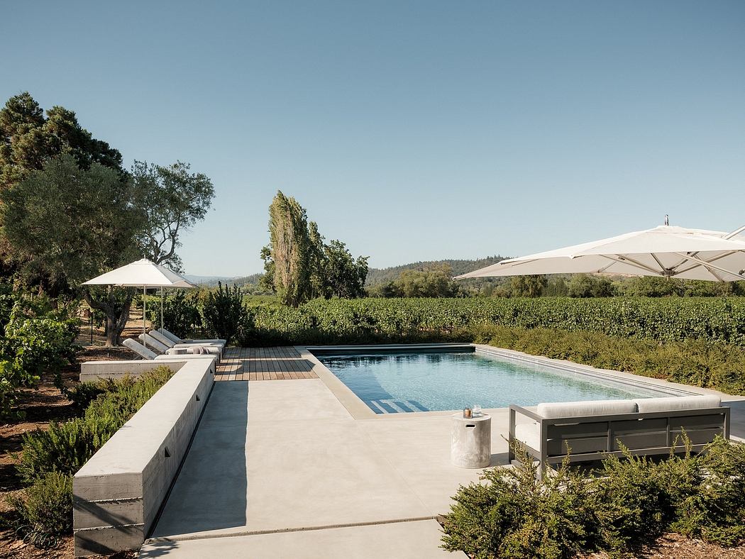 A minimalist outdoor pool and spa area surrounded by vineyard and mountain scenery.