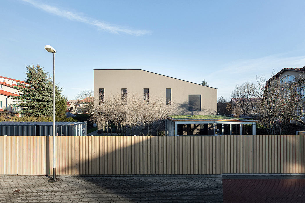 Modern, rectangular building with large windows and a wooden fence in the foreground.
