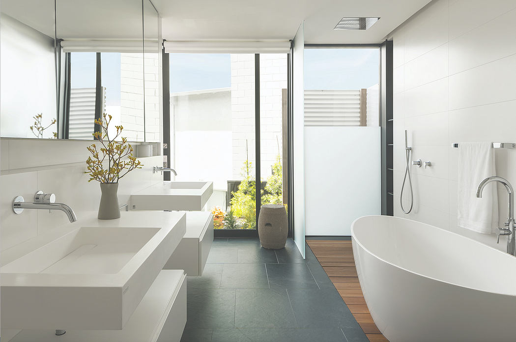 Sleek, modern bathroom with minimalist vanity, freestanding tub, and glass walls overlooking greenery.
