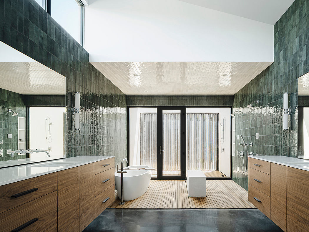 Spacious, modern bathroom with dark tile walls, wood vanities, and glass shower.