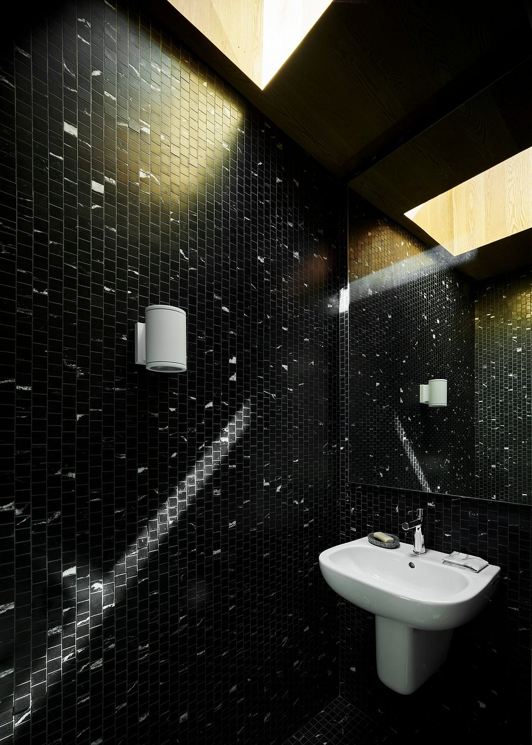 A sleek, modern bathroom with a black mosaic tile wall and a white pedestal sink.