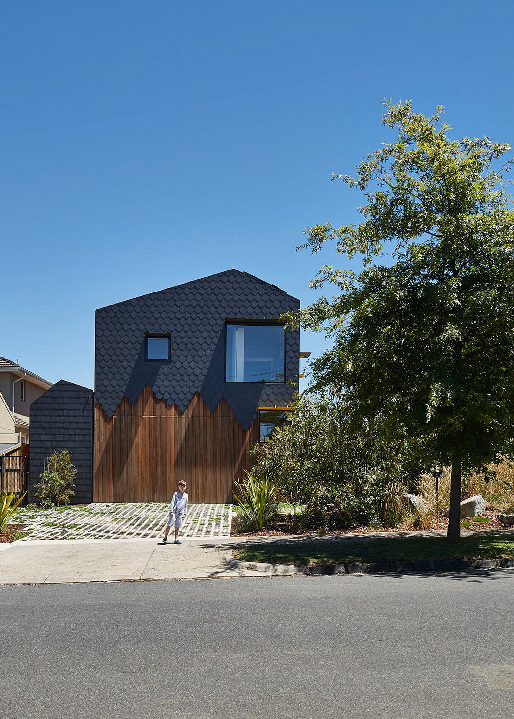 Striking modern home with dark slate roof and wooden exterior accents.
