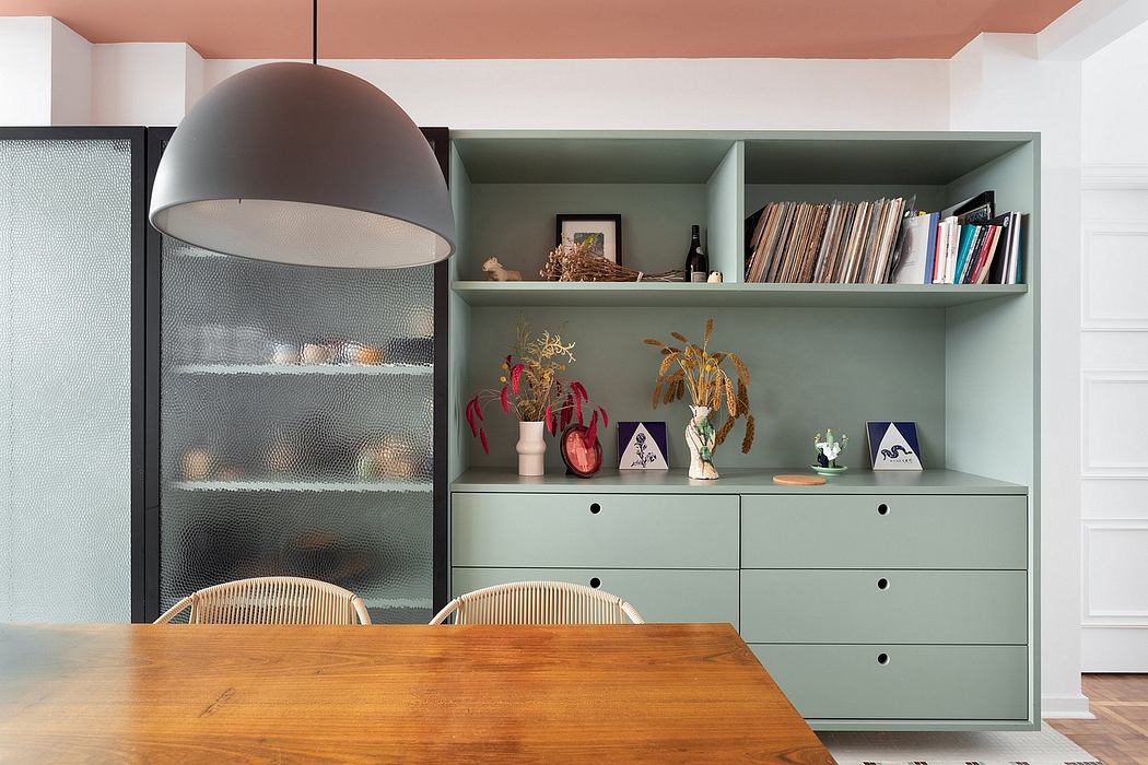 A modern, minimalist dining room with a glass-fronted cabinet, shelving, and a wooden table.