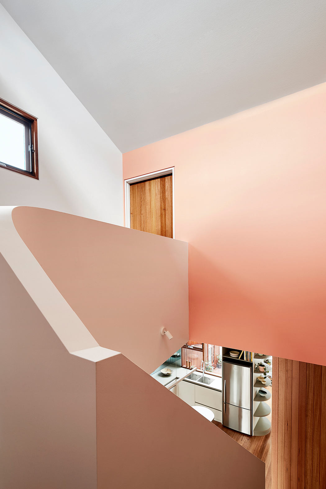 A modern, open-concept kitchen with warm, peach-toned walls and wood accents.