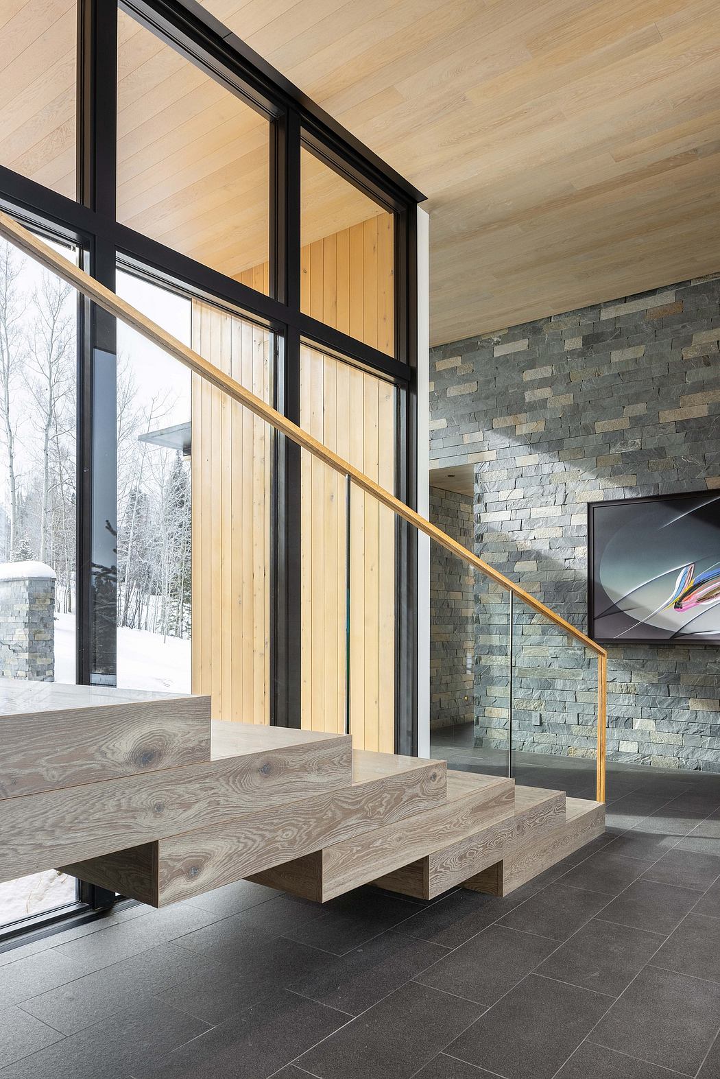 A modern, minimalist interior with large windows, wood paneling, and stone walls.