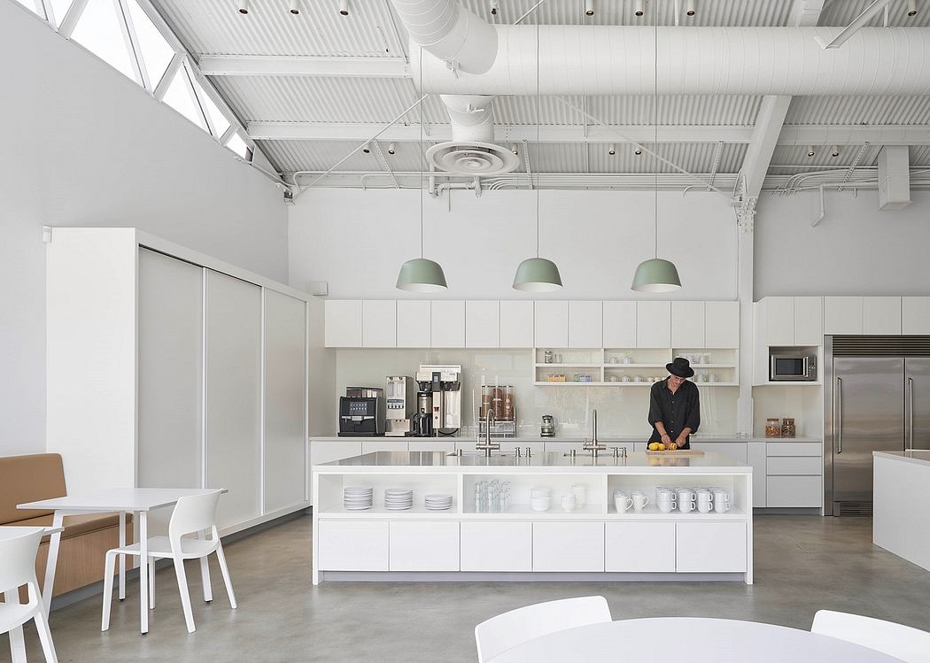 Sleek, minimalist kitchen with exposed ceiling beams, white cabinetry, and pendant lights.