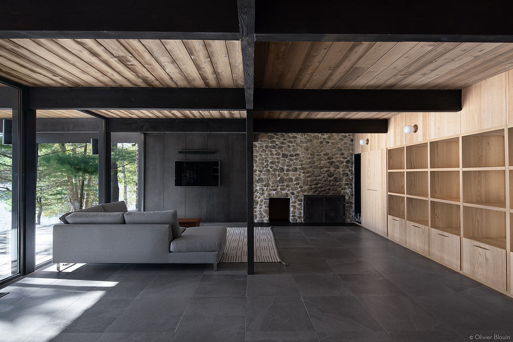 A modern, minimalist living space with stone walls, wooden beams, and slate flooring.