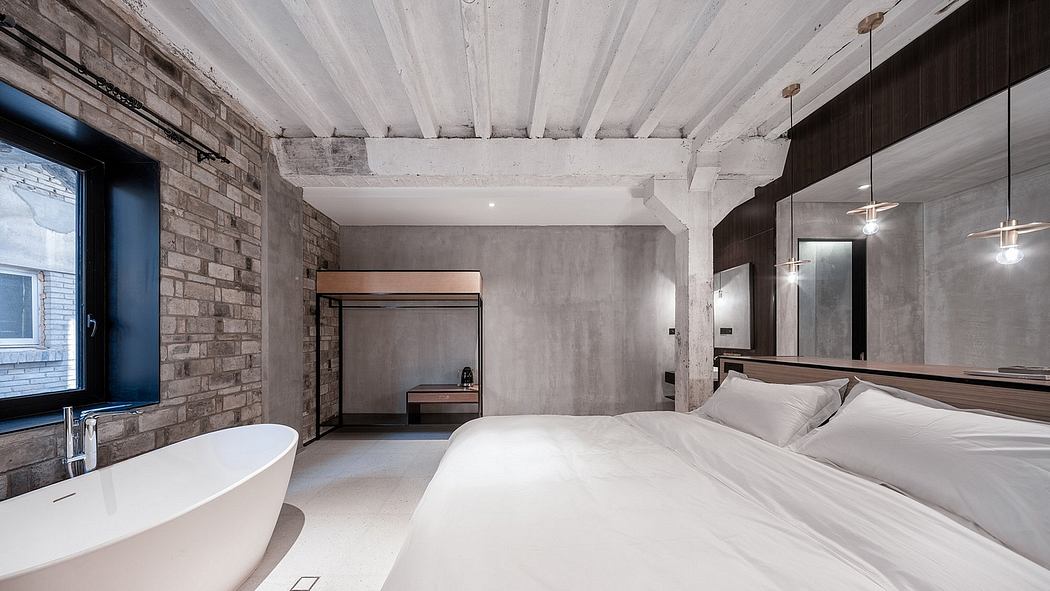 Modern loft-style bedroom with exposed brick walls, high ceilings, and a freestanding bathtub.