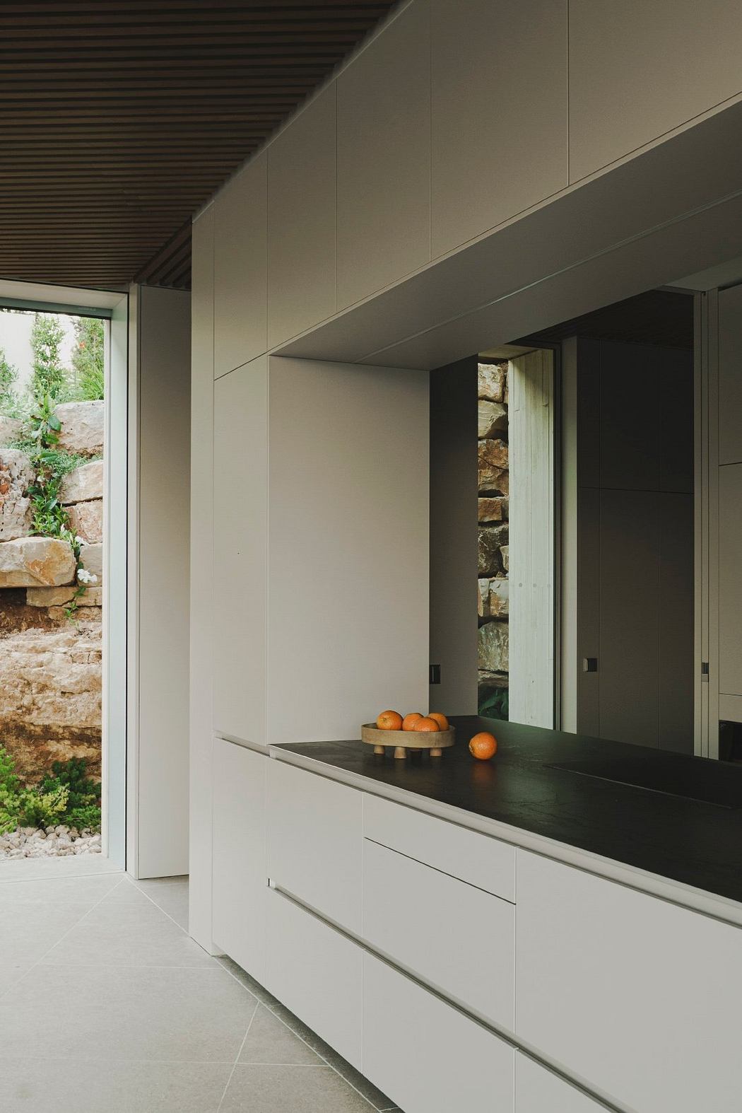 Minimalist kitchen design with clean lines, stone walls, and a black countertop.