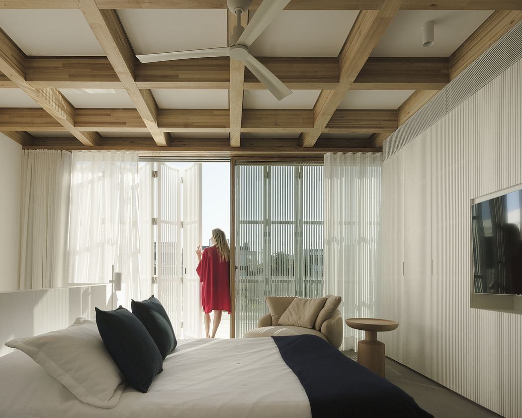 Stylish wooden ceiling beams, sliding glass doors, and neutral-toned furnishings create a serene atmosphere.