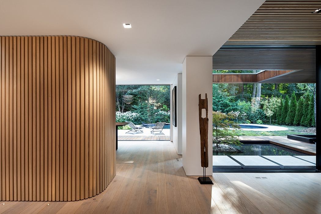 Elegant modern interior with wooden slats, glass walls, and lush outdoor view.