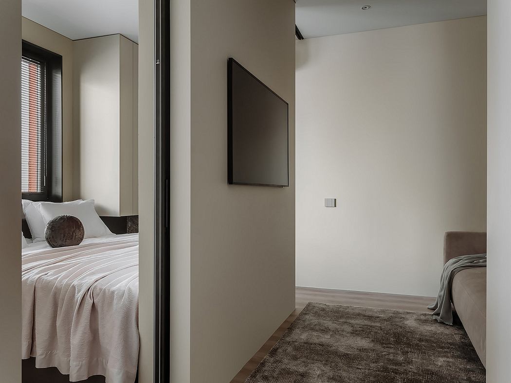 Modern, minimalist bedroom with monochromatic color scheme, large TV, and patterned rug.