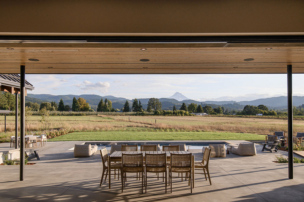 Wooden ceiling beams, patio furniture, and scenic countryside view in this outdoor setting.