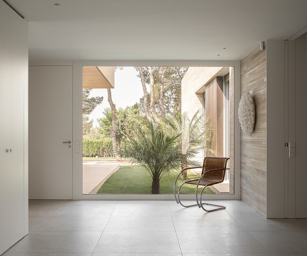 A modern, minimalist interior with large windows overlooking a lush, natural landscape.