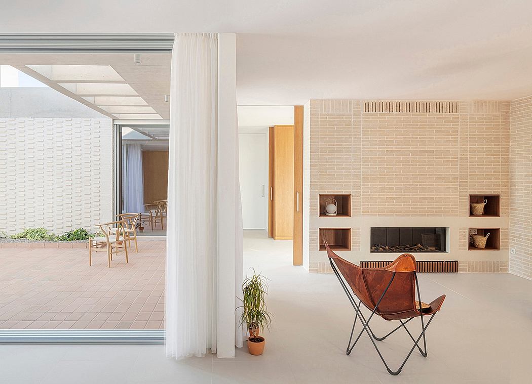 Expansive indoor-outdoor space with brick walls, open shelving, and a leather lounge chair.