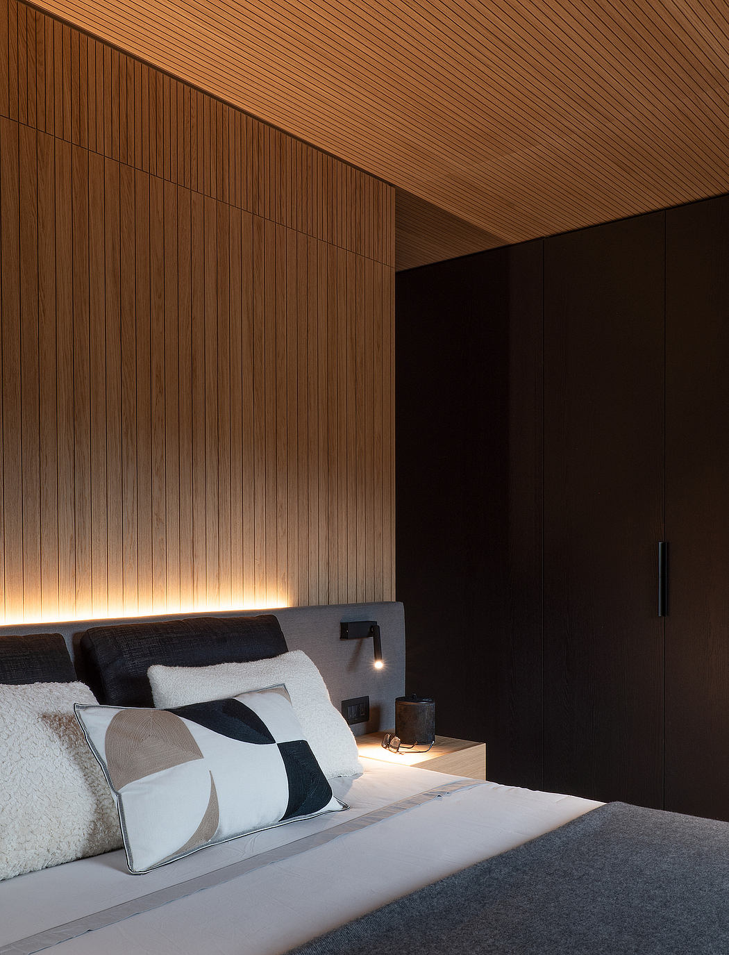 Modern bedroom with warm wooden panels, sleek nightstands, and ambient lighting.