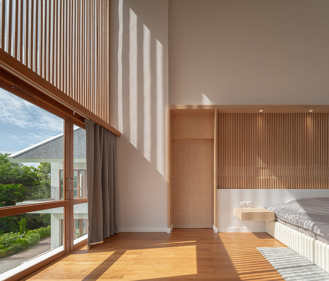 Bright, spacious bedroom with wooden slat wall paneling and large glass doors overlooking greenery.