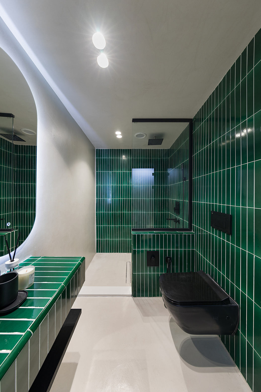 A modern bathroom interior with bold green tile walls, sleek fixtures, and recessed lighting.