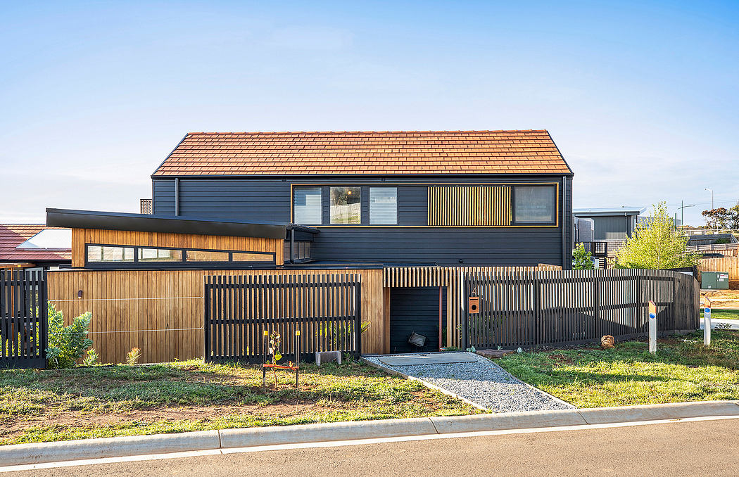 Modern, two-story home with wooden siding, sleek black accents, and a striking roofline.