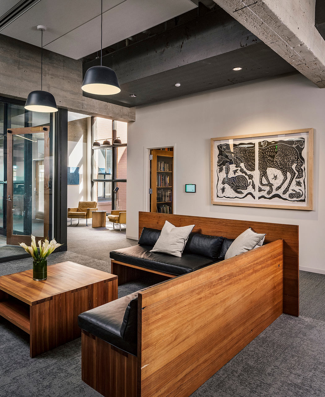 Sleek modern lounge with wooden furniture, concrete walls, and abstract artwork.