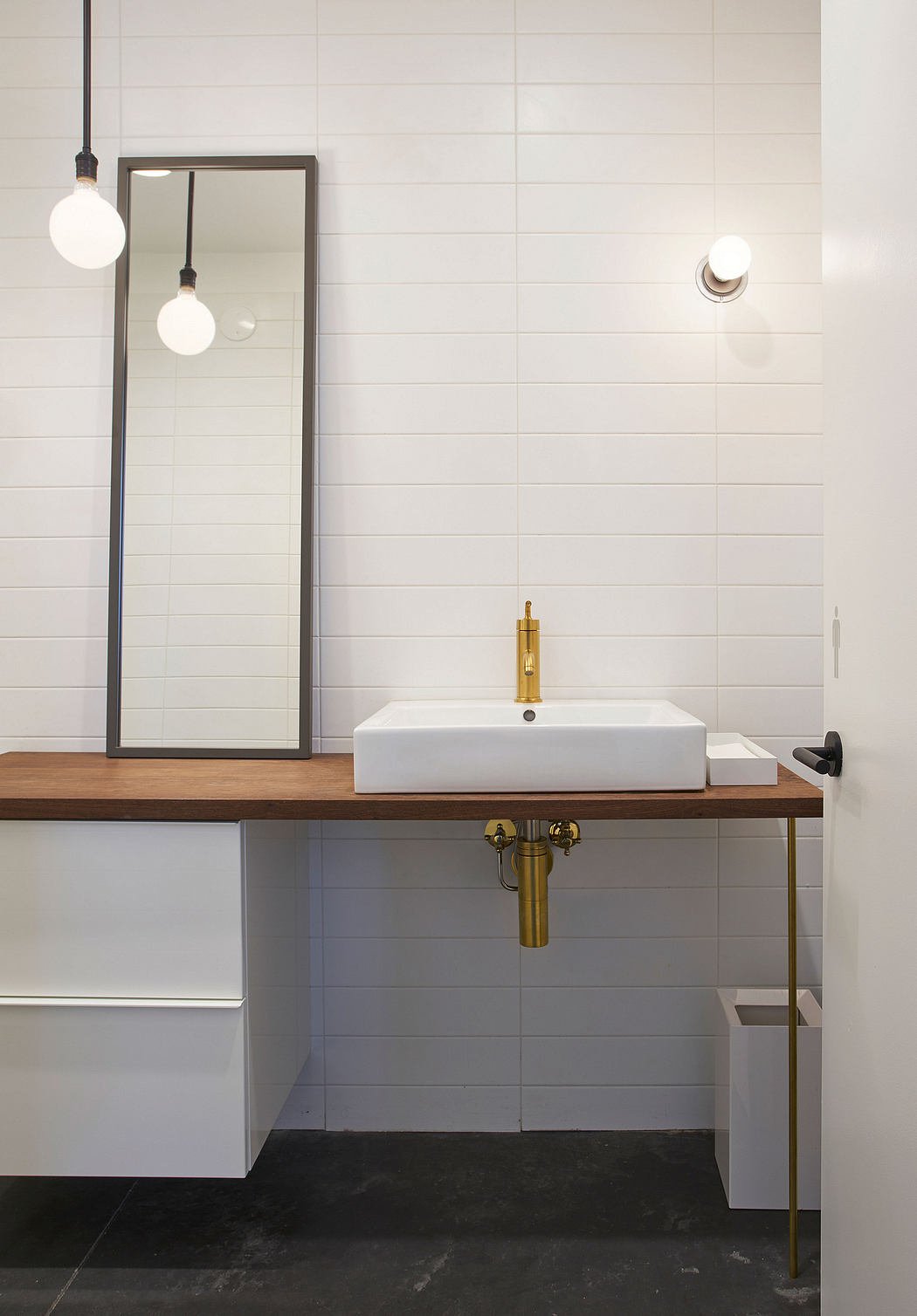 Modern bathroom with sleek vanity, vessel sink, gold faucet, and minimalist mirror.