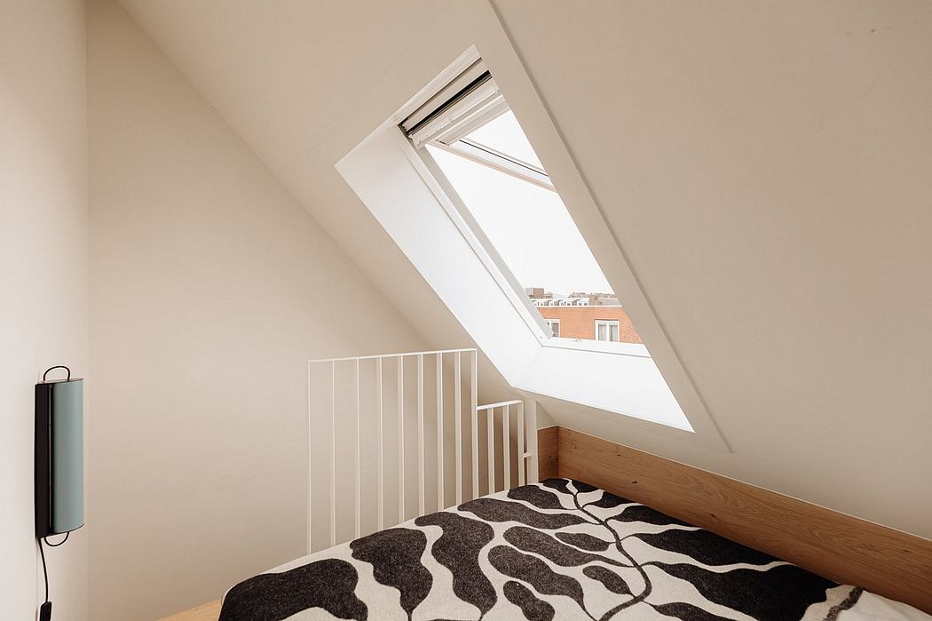 Bright attic bedroom with slanted ceiling, wooden accents, and large skylight.