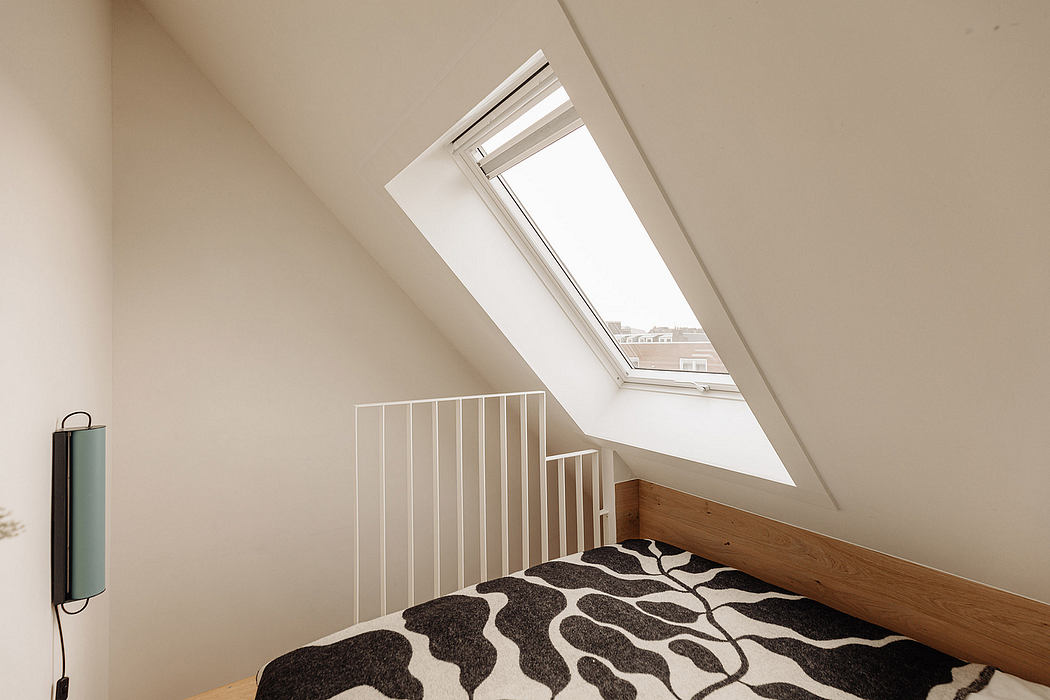 Cozy attic bedroom with slanted ceiling, skylights, and modern wooden railing.