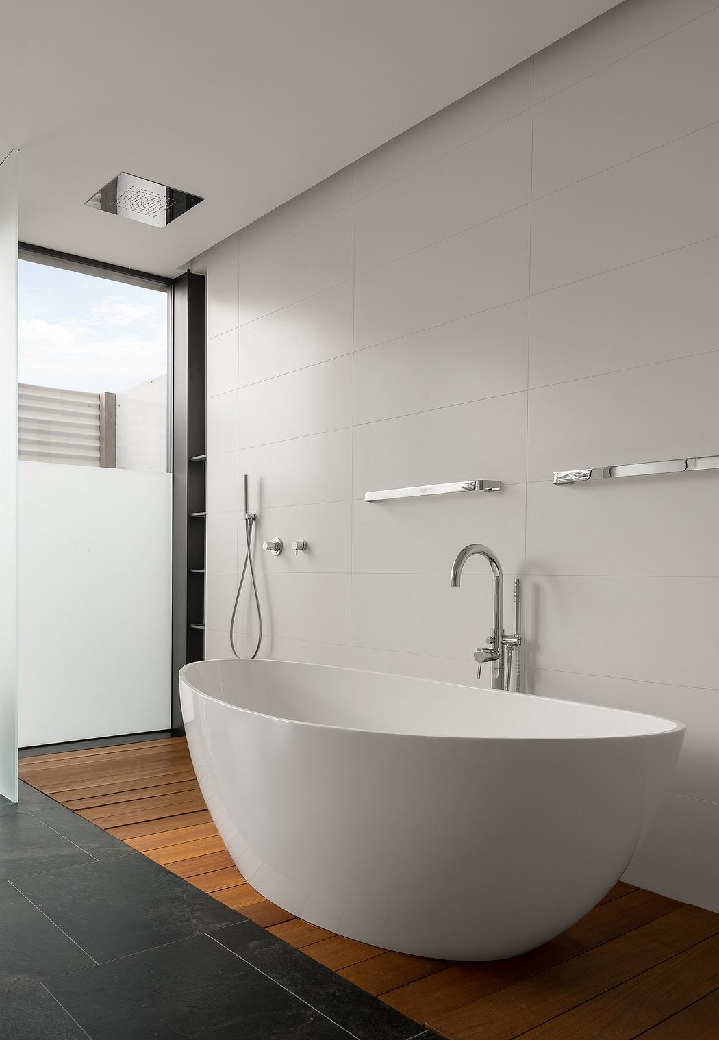 A modern bathroom with a freestanding bathtub, sleek fixtures, and a mix of materials.