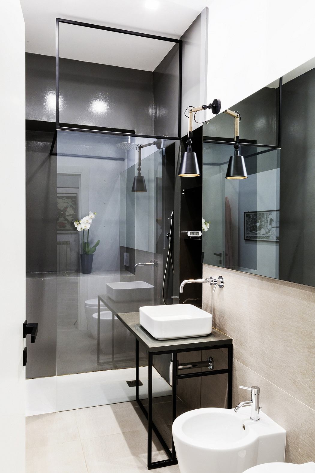 Modern bathroom featuring black-framed glass panels, vessel sink, and minimalist vanity.
