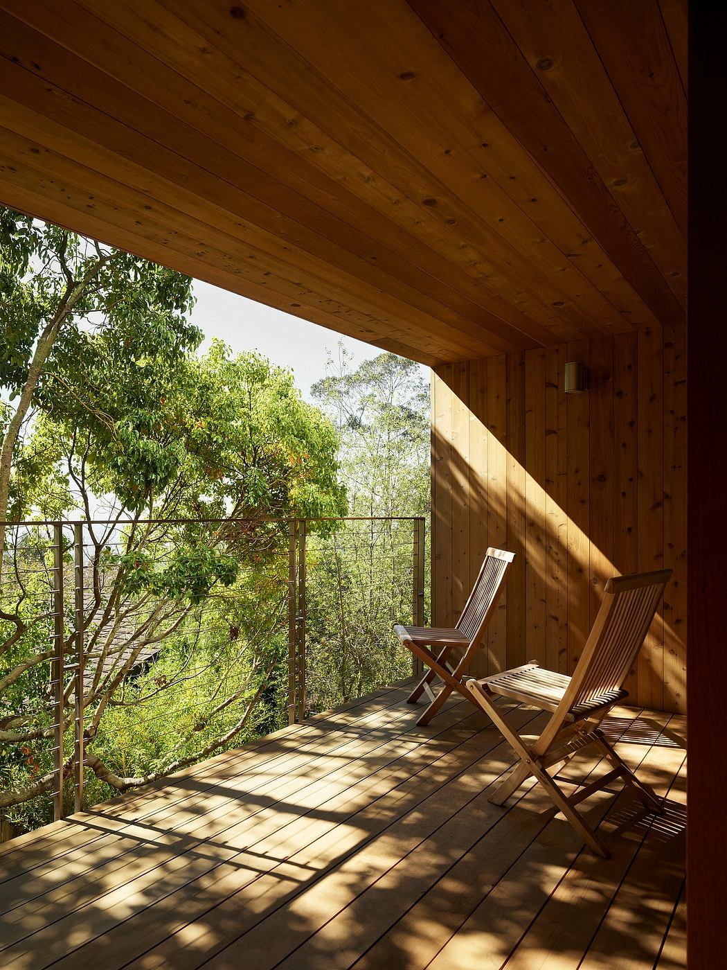 Cozy wooden porch with reclining chairs overlooking lush foliage, peaceful retreat.