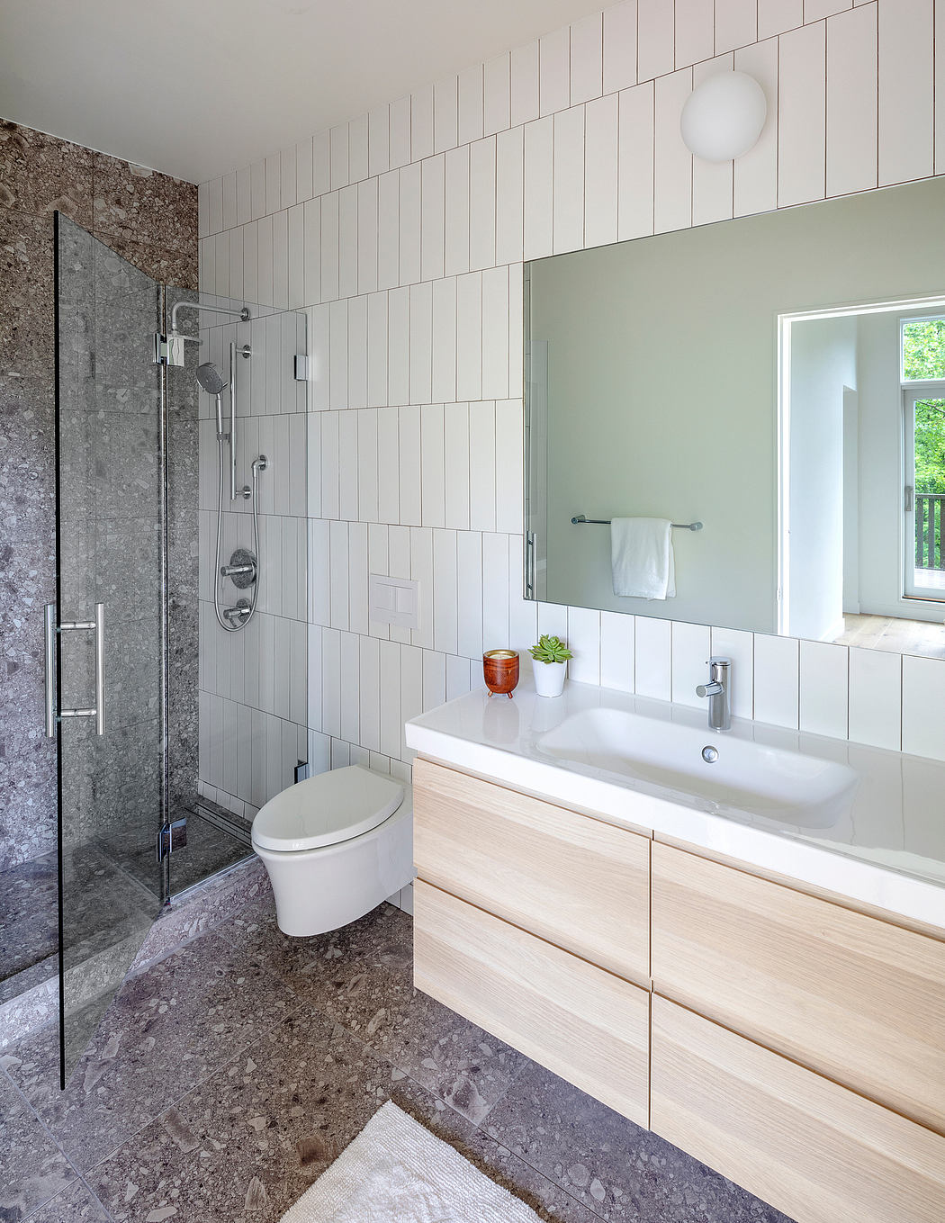 Sleek modern bathroom with tile walls, glass shower, and wood vanity.