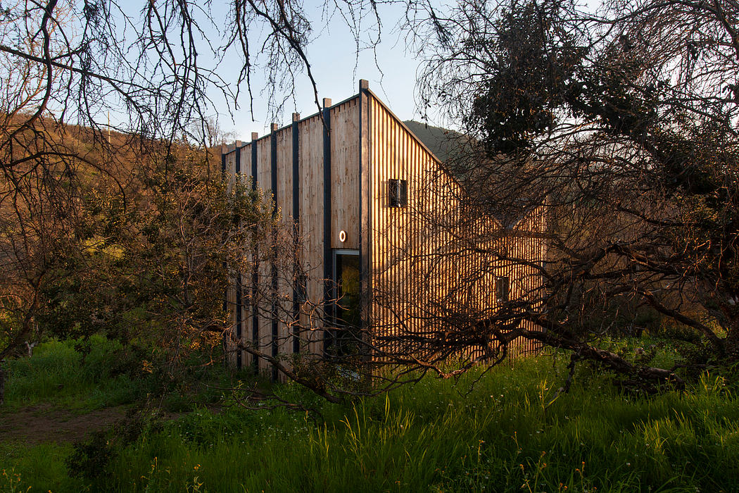 A rustic wooden structure with a distinctive slanted roof, partially obscured by foliage.