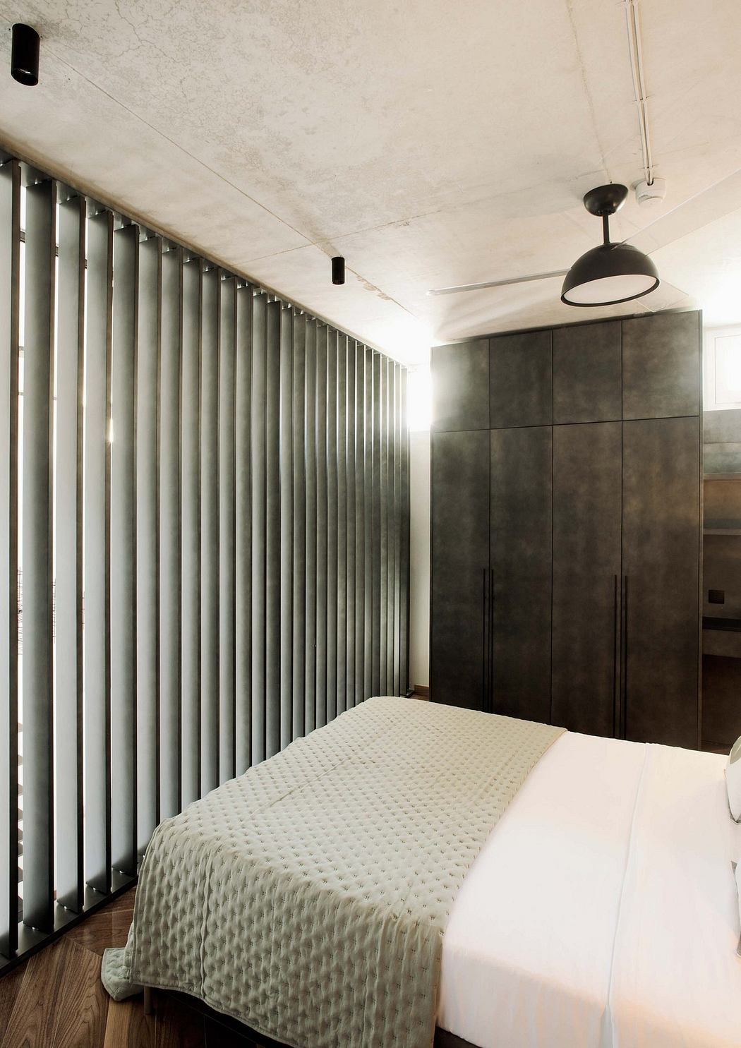 A minimalist bedroom with clean lines, black built-in furniture, and textured ceiling.