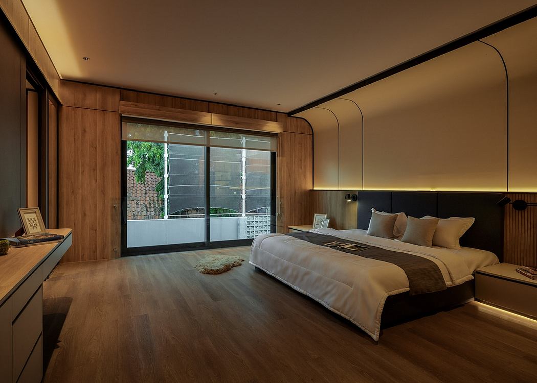 A modern bedroom with a wooden paneled wall, large windows, and warm lighting.