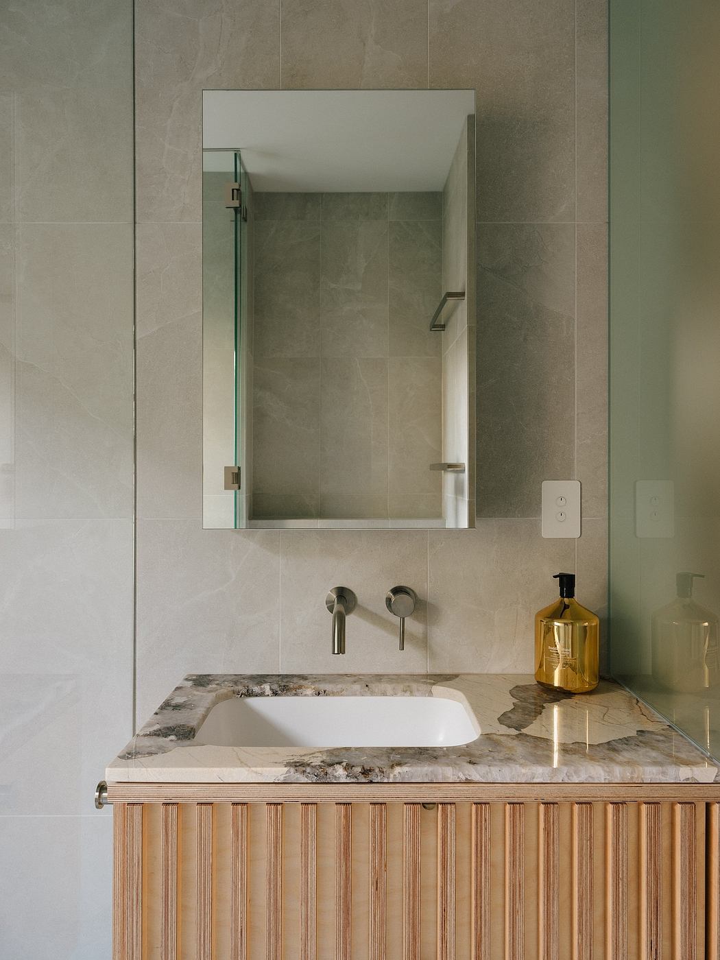 A modern bathroom featuring sleek mirror, marble vanity, and minimalist fixtures.