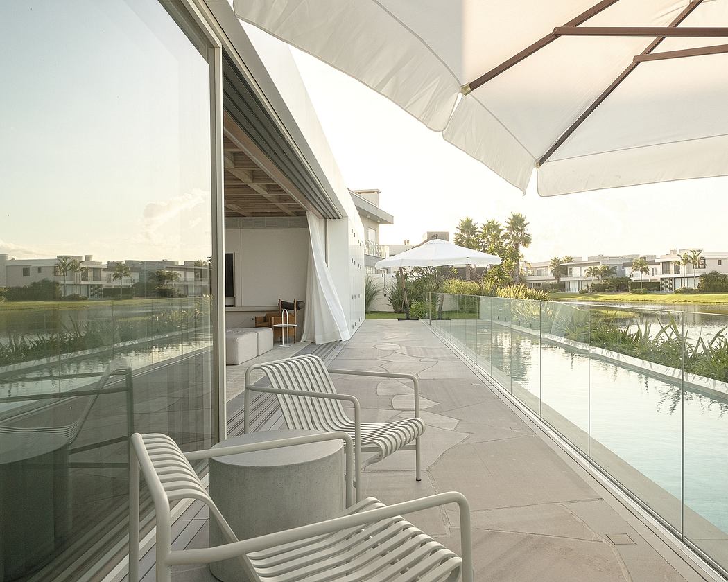 Modern terrace overlooking a pool, with sleek furniture and glass walls offering scenic views.