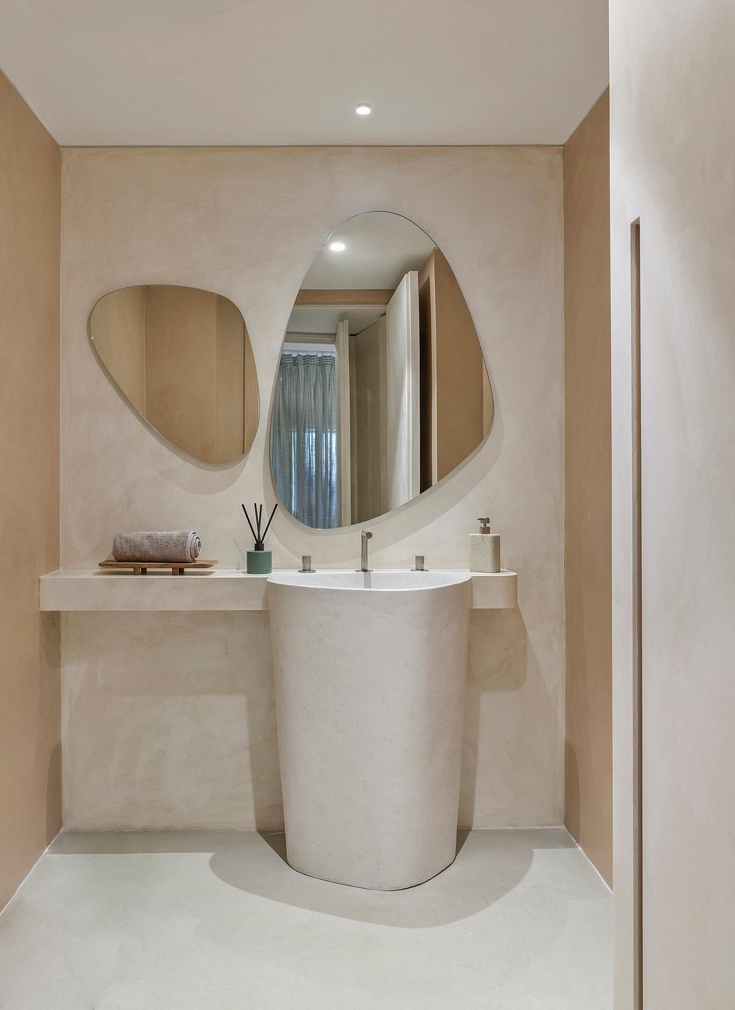 Elegant, minimalist bathroom with curved mirror, freestanding pedestal sink, and neutral tones.