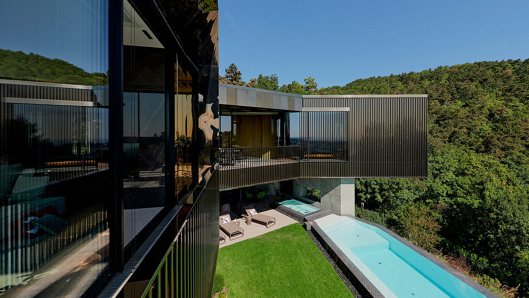 A modern glass-fronted home with a pool, surrounded by lush green trees.