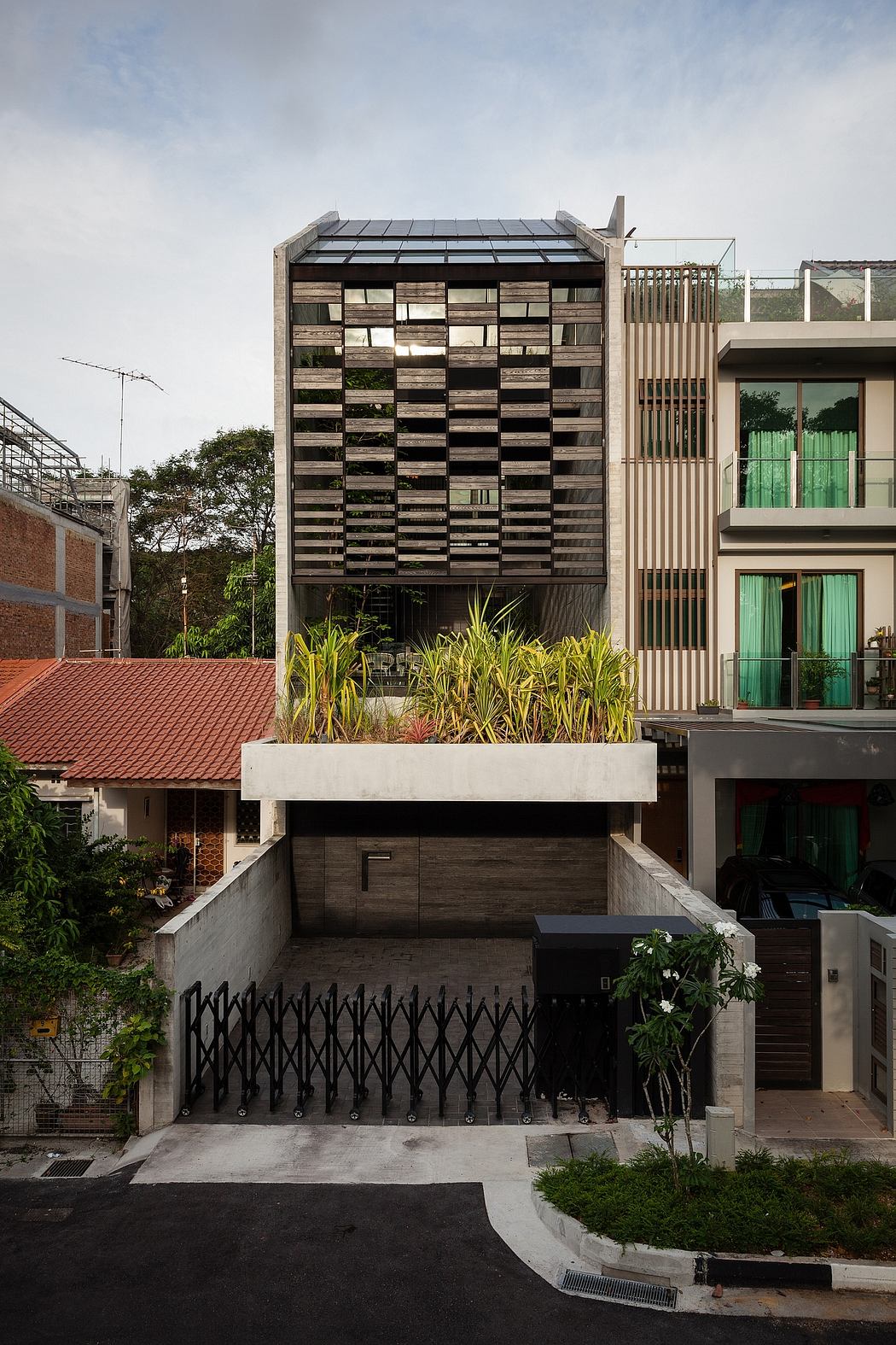 Striking architectural design featuring a geometric wooden facade, planters, and metal gates.